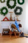 Boy kneeling on a chair in front of a sideboard stroking his cat — Stock Photo