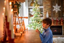 Menino em pé na frente de um aparador olhando para decorações de Natal — Fotografia de Stock