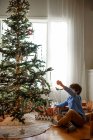 Boy hanging decorations on a Christmas tree — Stock Photo