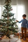 Junge steht vor einem Weihnachtsbaum — Stockfoto