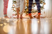 Close-up of three children's legs while decorating a Christmas tree — Stock Photo