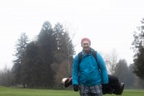 Человек стоит на поле для гольфа с сумкой для гольфа, Германия — стоковое фото