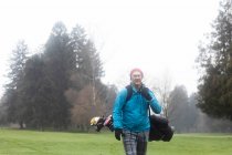 Hombre en un campo de golf llevando una bolsa de golf en invierno, Alemania - foto de stock