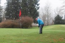 Mann legt im Winter einen Golfball auf einen Golfplatz — Stockfoto