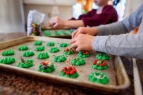 Двое детей стоят на кухне и украшают печенье — стоковое фото