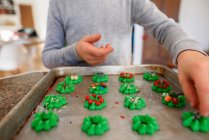 Menino de pé na cozinha decorando biscoitos — Fotografia de Stock