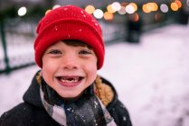 Retrato de um menino sorridente com dentes perdidos em pé na neve, Estados Unidos — Fotografia de Stock