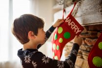 Хлопчик повісив різдвяний панчіх на каміні — стокове фото