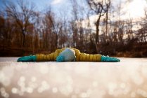 Девушка лежит на замерзшем пруду с протянутыми руками, США — стоковое фото