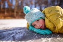 Ritratto di una ragazza sorridente sdraiata su uno stagno ghiacciato, Stati Uniti — Foto stock