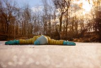 Menina deitada em uma lagoa congelada com os braços estendidos, Estados Unidos — Fotografia de Stock