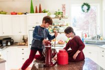 Deux enfants au comptoir faire gâteau à Noël intérieur de la cuisine décorée — Photo de stock