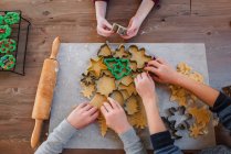 Дети делают рождественские печенья на столе, вид сверху — стоковое фото
