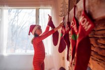 Chica colgando medias de Navidad en una chimenea - foto de stock
