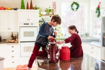 Zwei Kinder an der Theke backen Kuchen in weihnachtlich dekorierter Küche — Stockfoto