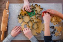 Діти роблять різдвяне печиво на столі, вид зверху — стокове фото