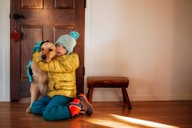 Girl sitting by her front door hugging a golden retriever dog — Stock Photo