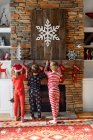 Tres niños colgando medias de Navidad en una chimenea - foto de stock
