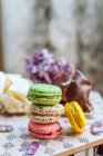 Macaroons doces coloridos com sobremesa e flores na mesa, vista de perto — Fotografia de Stock