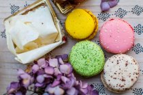 Macarons sucrés colorés avec dessert et fleurs sur la table, vue rapprochée — Photo de stock