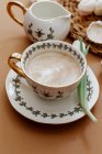 Xícara de café ao lado de um jarro com uma tulipa em uma mesa — Fotografia de Stock