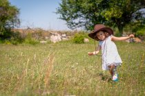 Девушка в летнем платье и ковбойской шляпе, бегущая по лугу, Болгария — стоковое фото