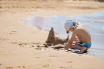 Garçon construisant un château de sable sur la plage, Corfou, Grèce — Photo de stock