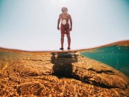 Niño de pie sobre una roca en el lago Superior, Estados Unidos - foto de stock