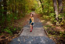 Girl running across a small footbridge, United States — Stock Photo