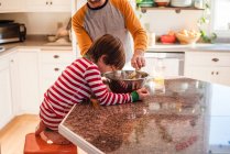 Boy helping his father bake in the kitchen — Stock Photo