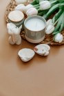 Tazza di caffè bianco con fiori e candele su sfondo chiaro. — Foto stock
