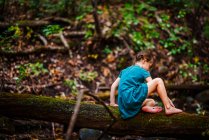 Chica trepando a lo largo de un árbol caído en el bosque, Estados Unidos - foto de stock