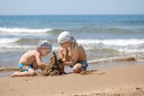 Два хлопця будують на пляжі піщаний замок Корфу, сірий — стокове фото