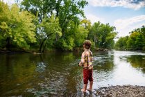 Niño de pie junto a un río de pesca, Estados Unidos - foto de stock