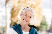 Portrait of smiling senior woman standing in park — Stock Photo