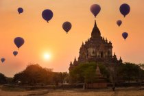 Balões de ar quente voando sobre um templo ao pôr do sol, Bagan, Myanmar — Fotografia de Stock