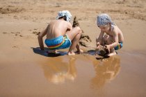 Два хлопця будують на пляжі піщаний замок Корфу, сірий — стокове фото