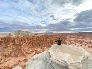 Rear view of a man sitting on cliff edge with his arms outstretched, Goblin Valley State Park, Utah, USA — Stock Photo