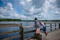 Boy and girl standing on a dock fishing in summer, United States — Stock Photo