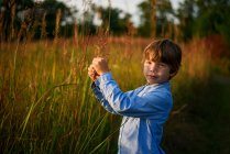 Porträt eines Jungen, der bei Sonnenuntergang auf einem Feld steht, Vereinigte Staaten — Stockfoto