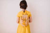Visão traseira de uma menina usando uma mochila no fundo branco — Fotografia de Stock