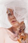 Conceptual beauty portrait of a woman wearing a veil with dried flowers on her face and neck — Stock Photo