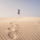 Femme sautant dans les airs au-dessus des dunes de sable, Espagne — Photo de stock