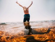 Boy standing in a lake with his arms raised, Lake Superior, Estados Unidos — Fotografia de Stock