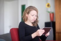 Femme à l'aide d'une tablette numérique soufflant ses joues — Photo de stock