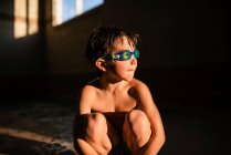 Ritratto di ragazzo che indossa occhiali subacquei seduto alla luce del sole — Foto stock