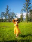 Chica de pie en un campo con un sombrero de verano, Brasil - foto de stock