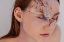 Концептуальный портрет женщины с высушенными цветами на лице — стоковое фото