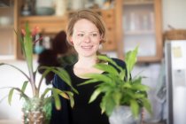Frau steht in Küche mit zwei Topfpflanzen — Stockfoto