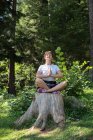 Frau sitzt meditierend auf Baumstumpf, Bosnien und Herzegowina — Stockfoto